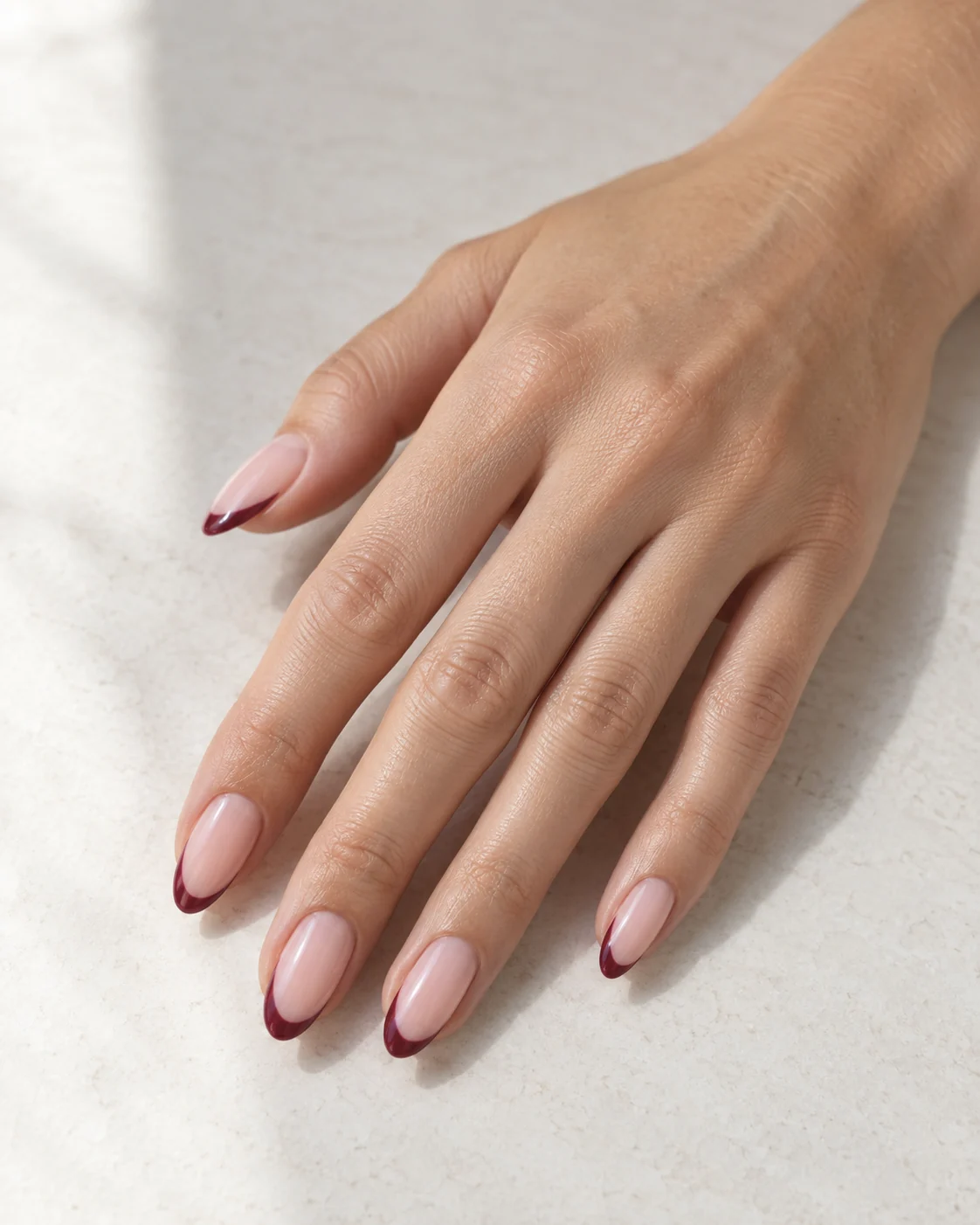 Delicate berry French tips on pale blush almond nails